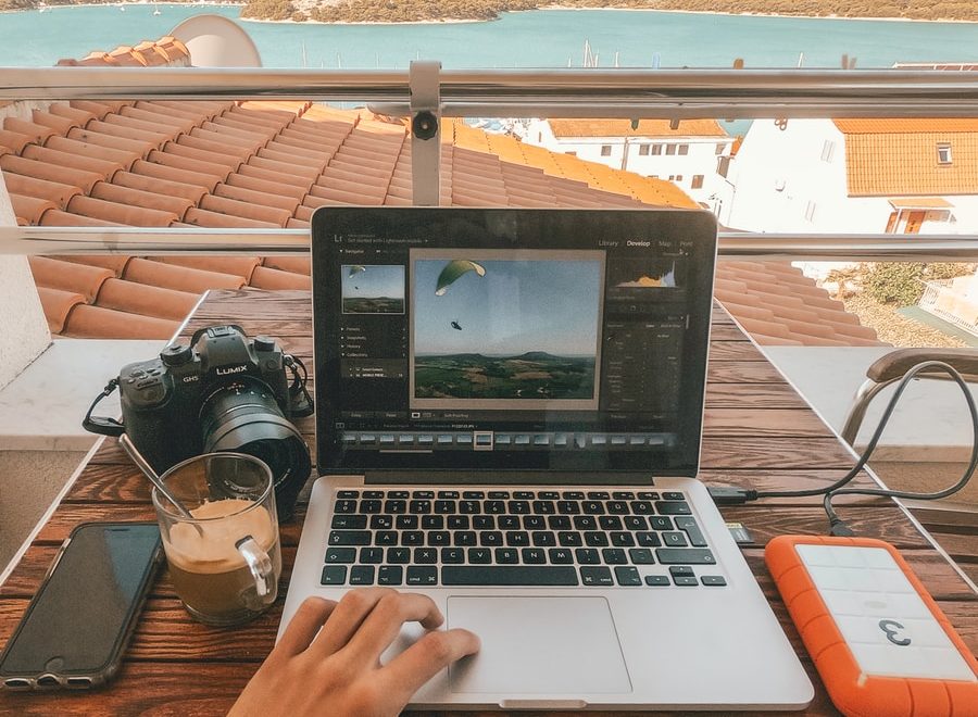 person holding MacBook Pro besides orange power bank